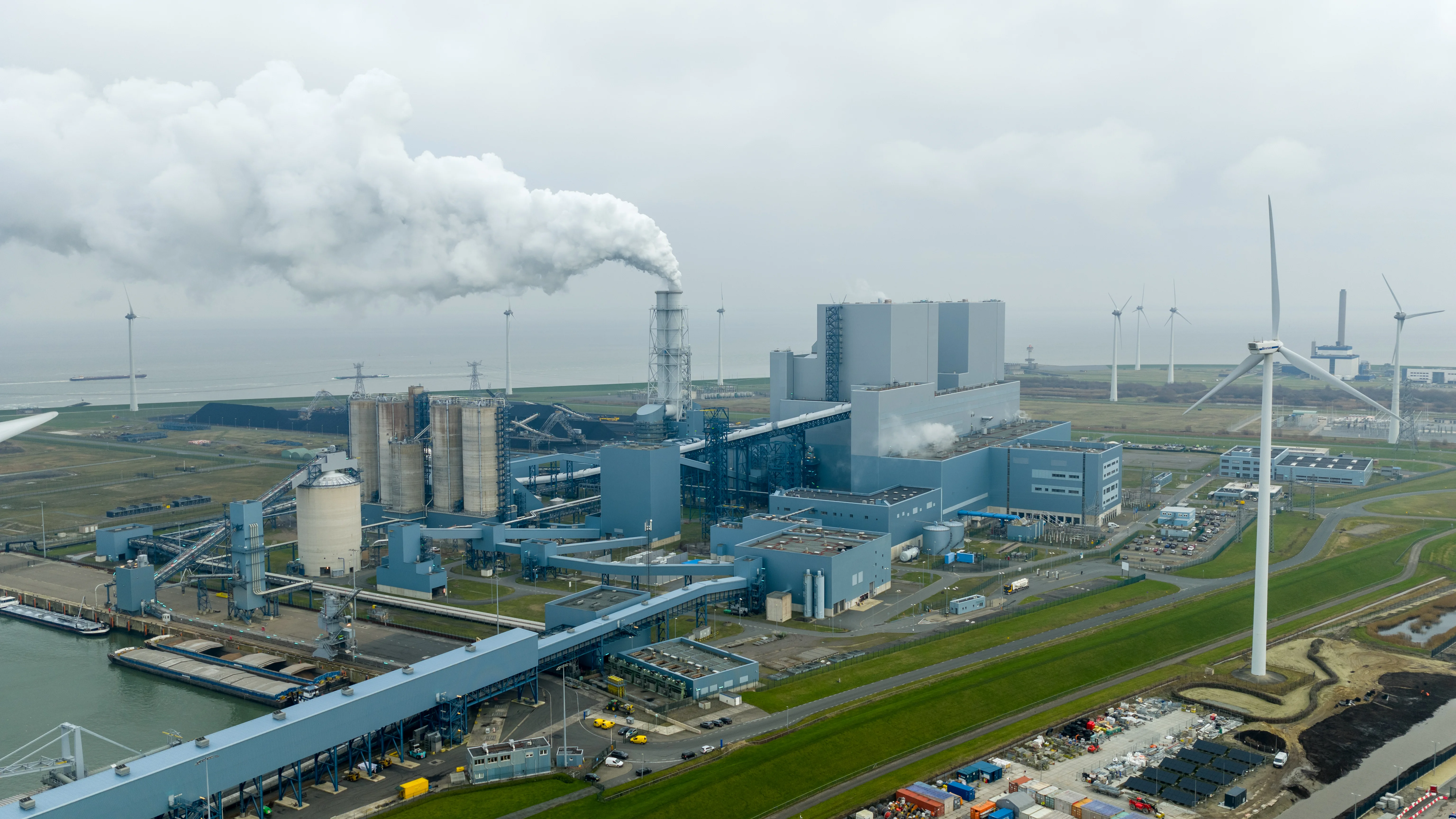 industrial complex aerial view with power plant, wind turbines, chemical plants, refineries, manufacturing facilities, professional drone photography, industrial infrastructure landscape