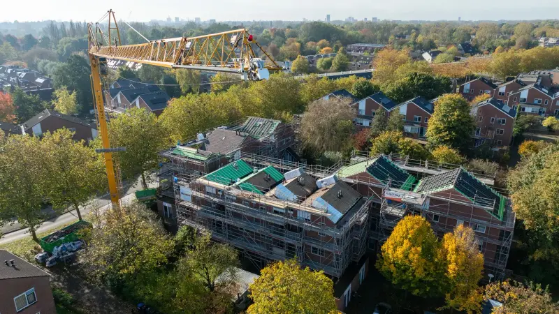 Rijtjeswoningen in de steigers met een gele torenkraan, vanuit de lucht