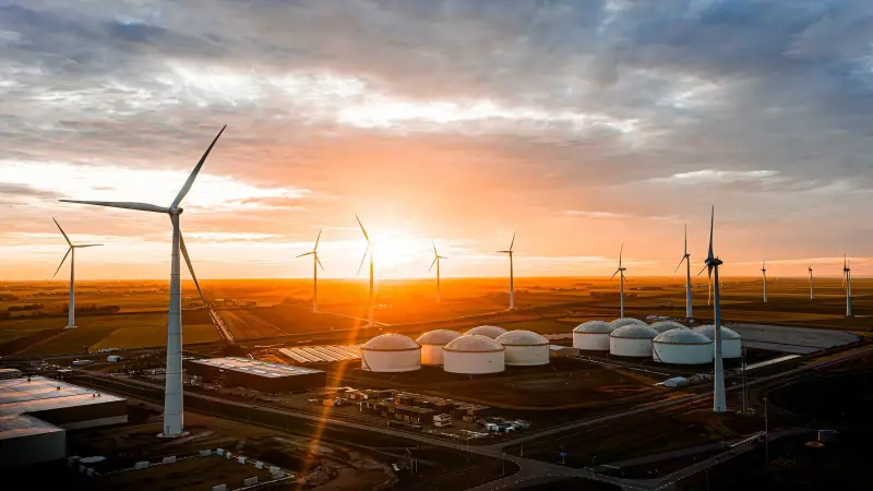 Windturbines en witte opslagtanks bij zonsondergang, vanuit de lucht gefotografeerd