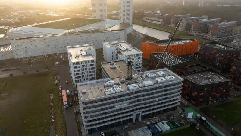 Appartementencomplex in aanbouw naast het stadion, met bouwkraan, in tegenlicht