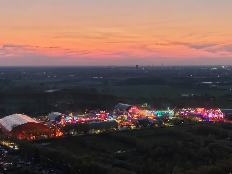 Festivalterrein met tenten en attracties bij schemering